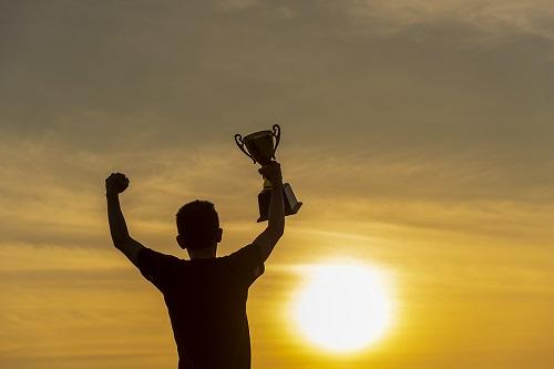 A person holding up a trophy in a celebratory pose
